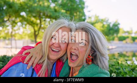 Amiche anziane felici che si abbracciano nel parco Foto Stock