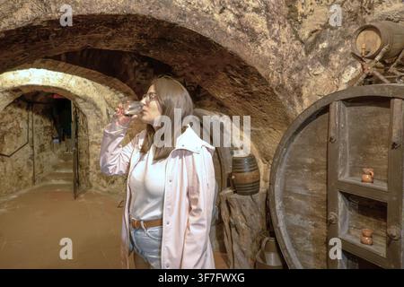 Donna che assaggia vino rosso in una cantina spagnola sotterranea Foto Stock