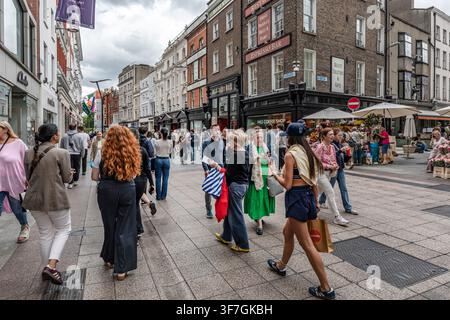 Acquisti e turisti passeggiano lungo le facciate storiche dei negozi di Grafton Street nel centro città di Dublino, Irlanda Foto Stock