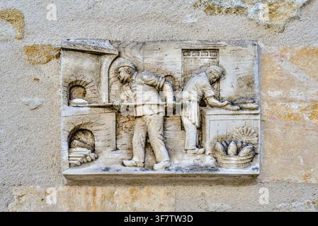 Pannello in gesso raffigurante due uomini che lavorano in una panetteria tradizionale con forno a legna - Bélâbre, Indre (36), Francia. Foto Stock