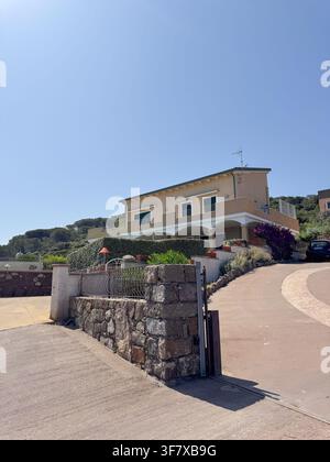 Casa moderna a due piani in Italia con un muro di pietra e un vialetto che porta all'ingresso. Circondata dalla vegetazione, la casa presenta grandi finestre e Foto Stock