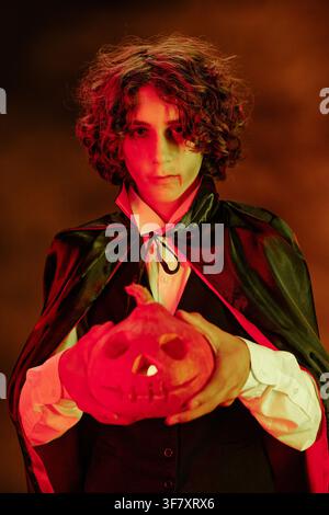 Ritratto di un adolescente in costume da vampiro che tiene una zucca di Halloween Foto Stock
