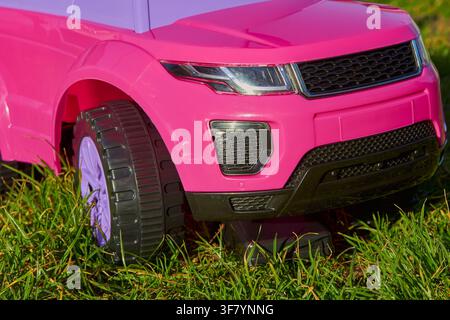 auto giocattolo per bambini per una bambina che guida all'aperto Foto Stock