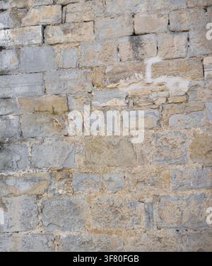 Muro di pietra della facciata di un vecchio edificio deteriorato dal tempo. Vista frontale. Foto Stock