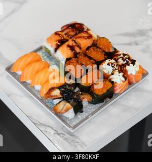 Vista ad angolo alto di un piatto di sushi misto con nigiri di salmone fresco, nigiri di angiuilla unagi, caviale di salmone ikra rosso gunkan e rotoli di salmone guarniti con Foto Stock