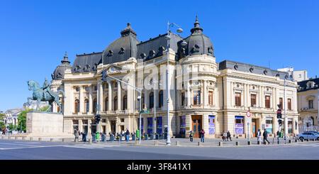 Statua equestre e biblioteca universitaria a Bucarest con un cielo blu chiaro sopra Foto Stock