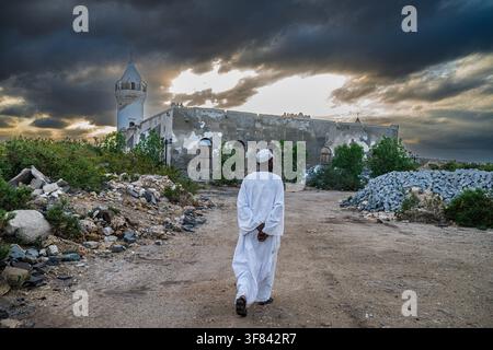 Uomo cammina sull'isola di Suakin esplorando siti storici di architettura in corallo al tramonto in Sudan Foto Stock