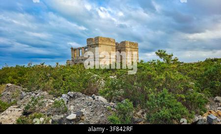 Rovine storiche si ergono tra la vegetazione sull'isola di Suakin sulla costa del Mar Rosso del Sudan Foto Stock