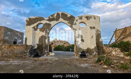 Ingresso storico verso le rovine sull'isola di Suakin, che mostra strutture di corallo e mura erose al tramonto nel Sudan Foto Stock