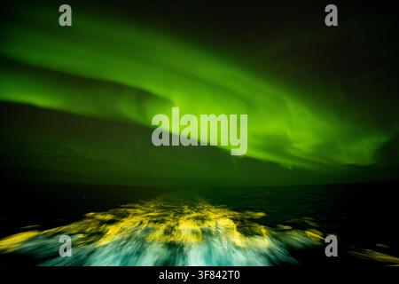 Il risveglio delle navi brilla sotto le luci del nord nello Stretto di Danimarca di notte Foto Stock
