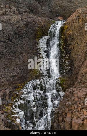 L'acqua scende a cascata lungo un pendio roccioso con muschio a Borgvig, Groenlandia Foto Stock