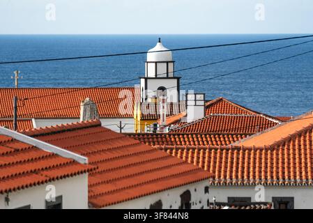Tetti con tegole rosse e torre della chiesa sopra l'Oceano Atlantico a Faja Grande sull'isola di Flores nelle Azzorre, Portogallo Foto Stock