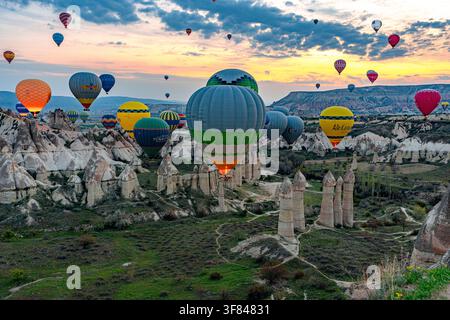 Mongolfiere volano sopra le chimere della Valle dell'Amore all'alba nell'Anatolia centrale, Turchia Foto Stock