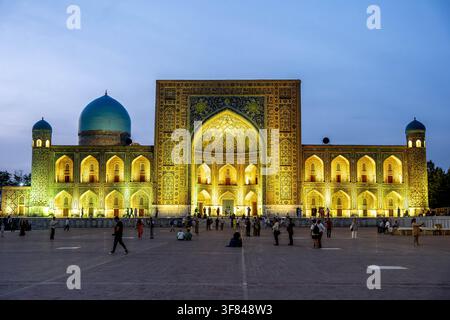 Vista serale del Registan con piazza affollata e luci colorate a Samarcanda, Uzbekistan Foto Stock