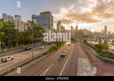 Vista della skyline della città al tramonto con strada trafficata ed edifici a Hong Kong Foto Stock