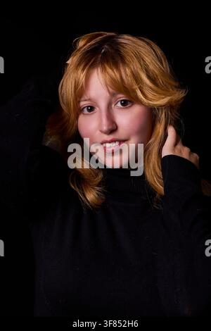 Giovane donna con capelli rossi e frangia che posa con sicurezza in un ritratto da studio Foto Stock