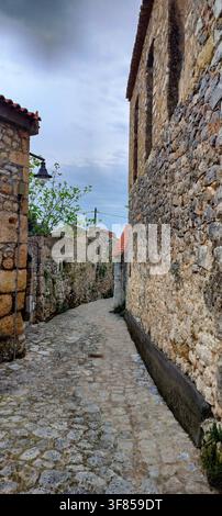 Vista verticale di un vicolo stretto fiancheggiato da case tradizionali in pietra nel villaggio storico di Oitylo, Mani, Grecia. Foto Stock