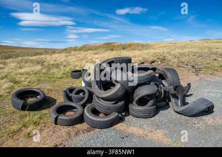 Cumulo di vecchi pneumatici per auto abbandonati su un lato della strada rurale nelle Yorkshire Dales, causando un rischio di inquinamento. Foto Stock