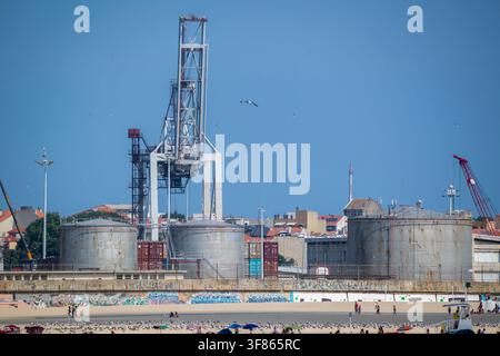 Vista dell'infrastruttura della raffineria con grandi serbatoi di stoccaggio e una gru alta vicino alla spiaggia a Matosinhos, distretto di Porto, Portogallo. Foto Stock