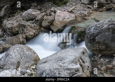 Acqua che scorre velocemente tra grandi rocce angolari in una natura aspra, un'esposizione lunga di un fiume a Fuessen, in Baviera Germania Foto Stock