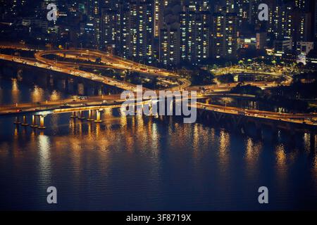 Vista notturna dettagliata dell'interlock del ponte sul fiume Han e dei riflessi del traffico sulla superficie dell'acqua a Seoul. Foto Stock
