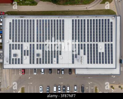 Vista aerea dall’alto di un grande tetto di edificio commerciale coperto da pannelli solari, concetto di energia rinnovabile e infrastruttura aziendale sostenibile. Foto Stock
