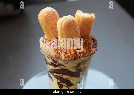 Variante di dessert italiano Tiramisu servito in un bicchiere. Il Tiramisu è fatto con biscotti savoiardi, mascarpone e uova. È aromatizzato al caffè Foto Stock