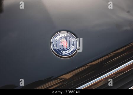 Lindau, Svizzera, 9 agosto 2026. Primo piano dettagliato dell'emblema rotondo blu Saab Scania con stemma del grifone sul cofano metallico scuro di un'auto. Foto Stock