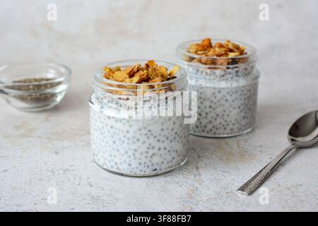 Pudding di chia con granola in barattoli di vetro e cucchiaio vista frontale Foto Stock