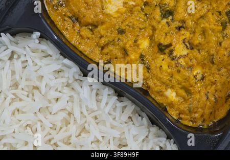 Piatto pronto di pollo al curry e riso cibo piccante in contenitore di plastica vista piatta primo piano. Foto Stock