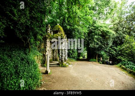 Bom Jesus do monte: Antico arco di pietra coperto di muschio e viti. Il sentiero conduce in una fitta foresta verde. La natura riprende una struttura abbandonata. Serena, q Foto Stock