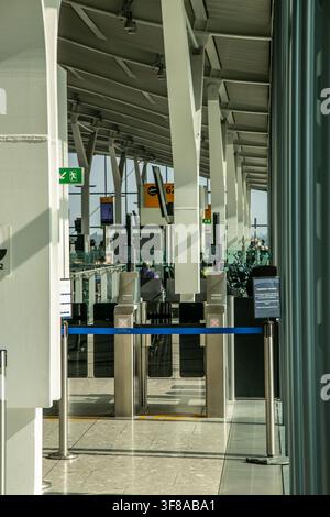 Gate di imbarco C63 nel Terminal 5C dell'aeroporto di Londra Heathrow (LHR), Regno Unito. L'area del gate dell'aeroporto è dotata di barriere per la fila dei passeggeri Foto Stock