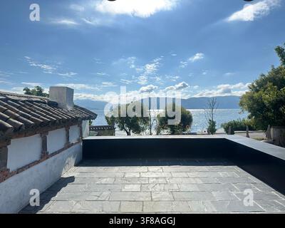 Terrazzo panoramico soleggiato con fiori in vaso che si affaccia sul lago Erhai a Dali, Yunnan, Cina. Foto Stock