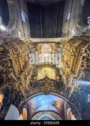 Interno grandioso e ornato di cattedrale con decorazioni dorate. Intagli intricati e opere d'arte dettagliate riempiono lo spazio. La luce filtra attraverso le finestre alte. Foto Stock