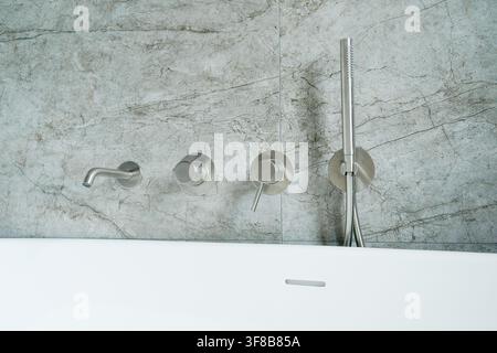Primo piano di comandi moderni per bagno montati a parete e beccuccio con una lunga asta doccia a mano in un bagno contemporaneo. Foto stock perfetta per l'idraulica Foto Stock