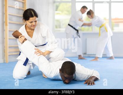 Gli sportivi di Cosmopolite si allenano con le mani striscianti durante l'allenamento in aikido Foto Stock