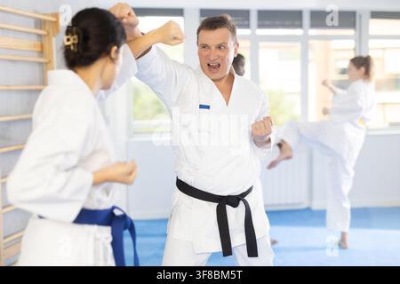 Donna e uomo in kimono e cinture sparring durante l'allenamento di karate Foto Stock