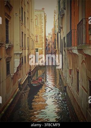 San Polo, Venezia, Italia - 10.07.2016: Gondola veneziana tradizionale che scivola sull'acqua calma in un vicolo stretto con muri gialli scoloriti Foto Stock