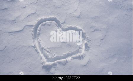 Cuore di neve. Motivo romantico invernale. Forma a cuore nella neve. Foto Stock