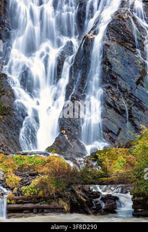Cascata montana che scorre rapidamente su rocce scure e frastagliate Foto Stock