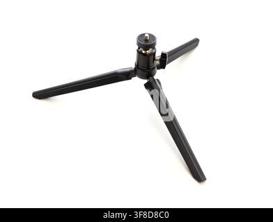 Un piccolo treppiede nero per fotocamera si trova su uno sfondo bianco Foto Stock