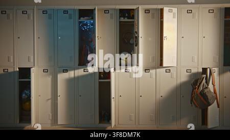 Interno autentico di un corridoio di una scuola elementare moderna con armadietti aperti che rivelano oggetti quotidiani degli studenti. Ambiente di apprendimento organizzato, strutture educative e concetto di vita nel campus moderno. Foto Stock