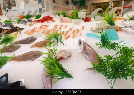 Pesce fresco e frutti di mare esposti sul ghiaccio al banco di un mercato locale, che mostrano prodotti mediterranei di prima qualità e il commercio giornaliero di alimenti costieri. Foto Stock