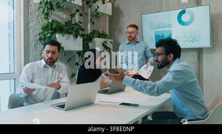 Quattro diversi uomini di team multietnici di affari donna d'affari in hijab che discutono idee briefing in ufficio indoor analisi strategia colloqui interattivi Foto Stock