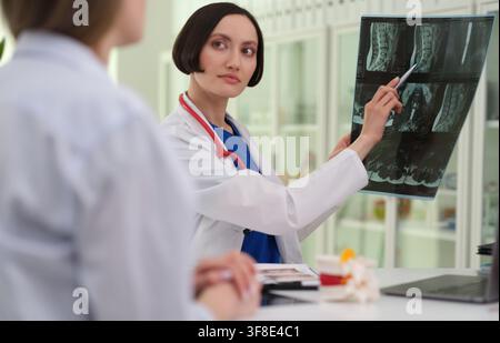 Dottoressa indica una scansione della colonna vertebrale durante la consulenza del paziente Foto Stock