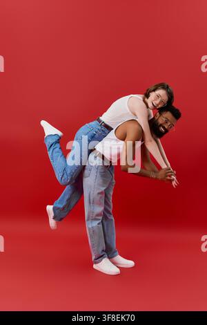 Una coppia multirazziale amorevole condivide un momento giocoso e romantico, posando in abiti chic. Foto Stock
