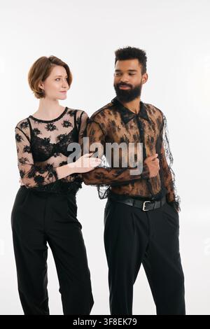 Una coppia multirazziale amorevole condivide un momento gioioso in abiti eleganti, in piedi insieme con i sorrisi. Foto Stock