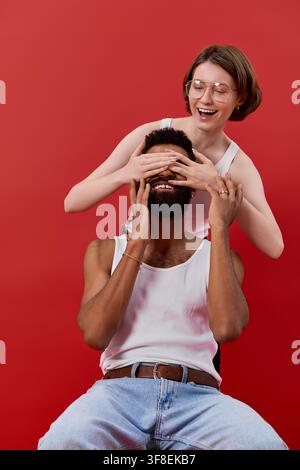Una coppia elegante condivide un momento giocoso, evidenziando il loro amore su uno sfondo vivace. Foto Stock