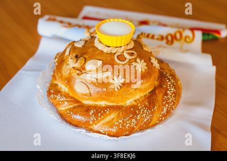 Un tradizionale pane rotondo per matrimoni decorato con intricati motivi di pasta e un portasalino è posato su un panno bianco. Foto Stock
