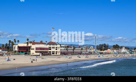 Passeggiata sulla spiaggia di Santa Cruz e spiaggia principale in una giornata di sole, con giostre del parco divertimenti, palme e visitatori accanto alla baia di Monterey a Santa Cruz, California Foto Stock